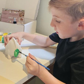 Child enjoying calm, inclusive dinosaur craft kit at home.