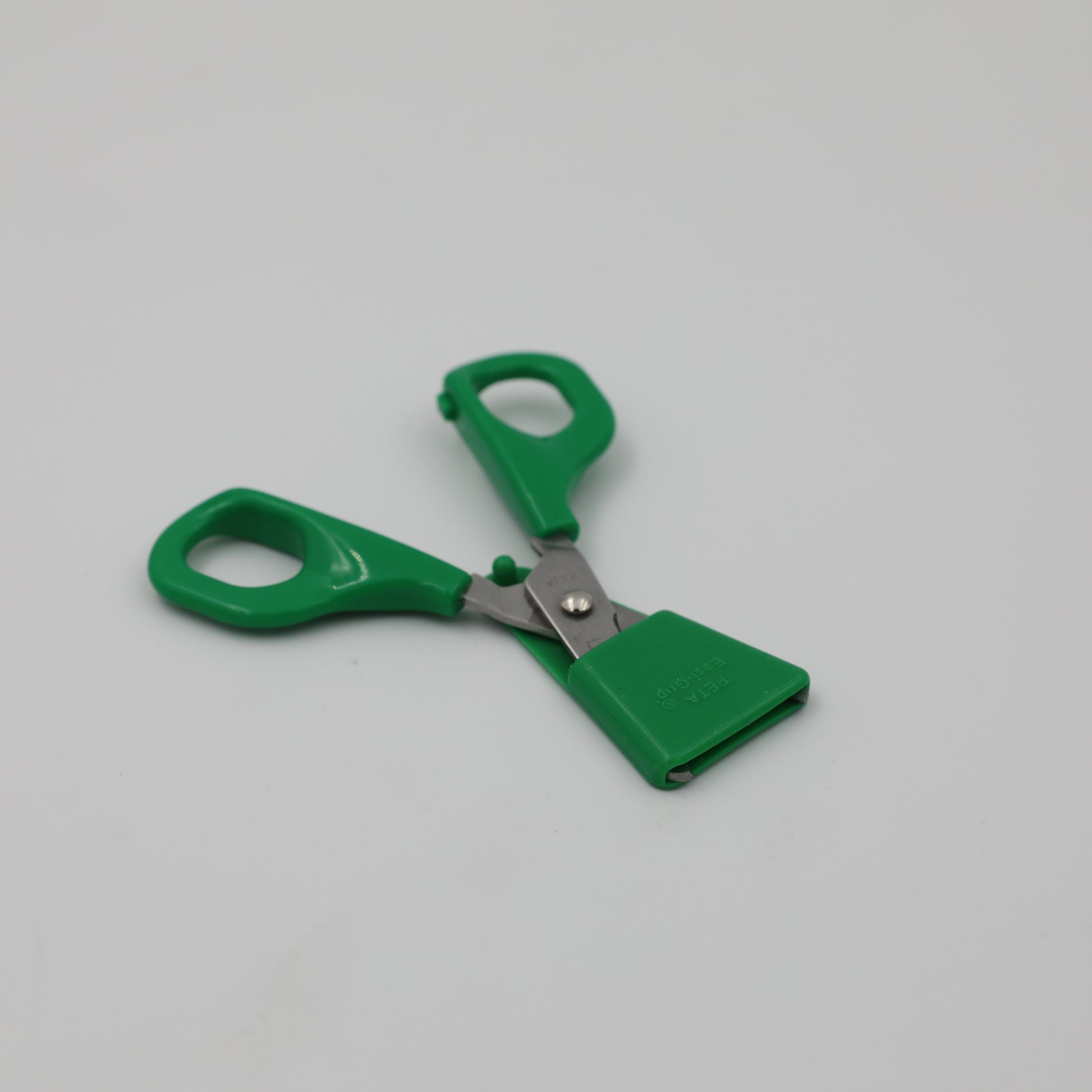 Left-handed green Child Self-Opening Scissors blade guard for safe storage.